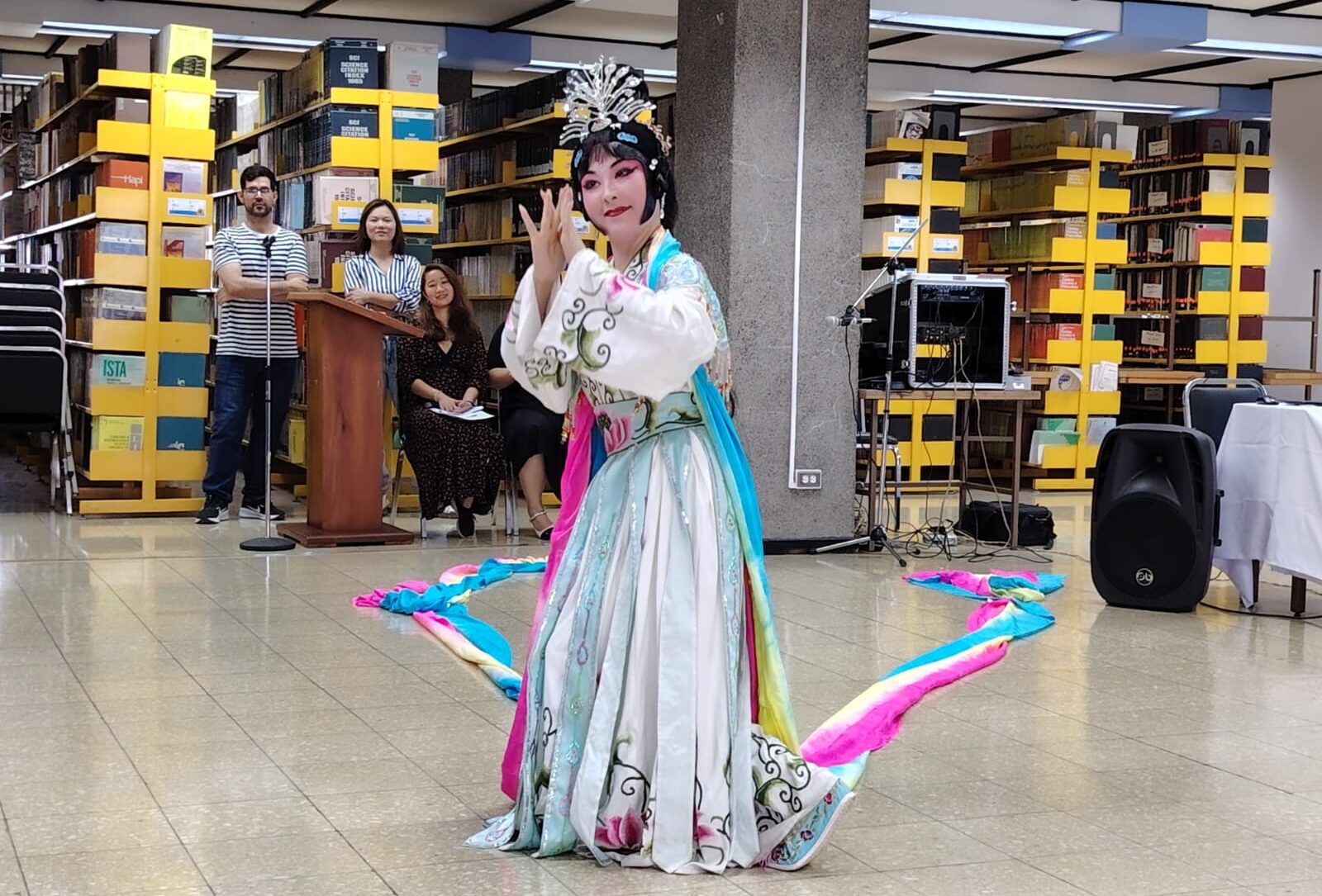 Presentación artística de baile realizada en un espacio de biblioteca con público observando la actividad